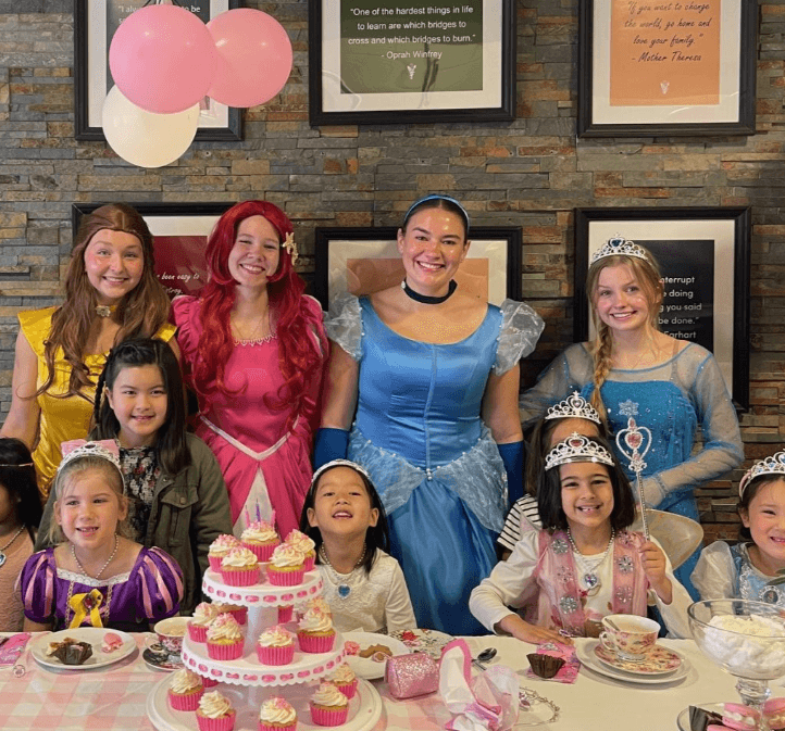 a group of people posing for a photo in front of a birthday cake