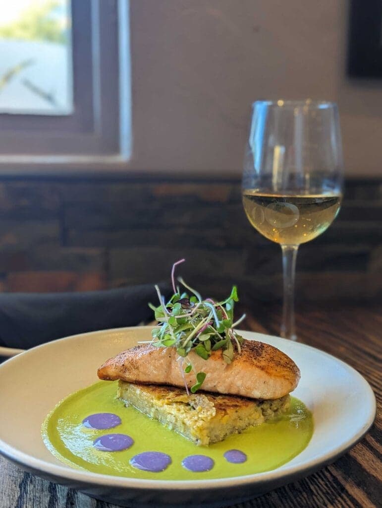 a close up of a plate of food and a glass of wine