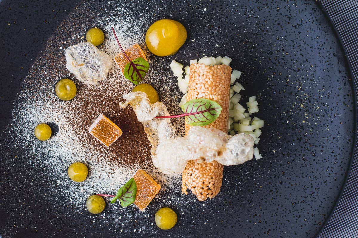 Puffed grass-fed beef tendon with bone marrow panna cotta, benne seed tuile, onion ash, and pickled papaya at PY Steakhouse (Credit: Jackie Tran)