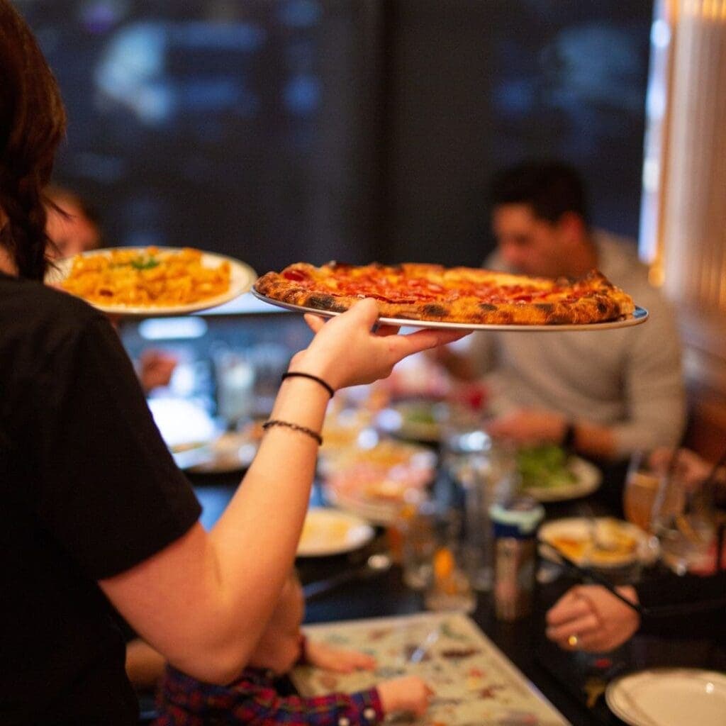 a group of people sitting at a table eating pizza