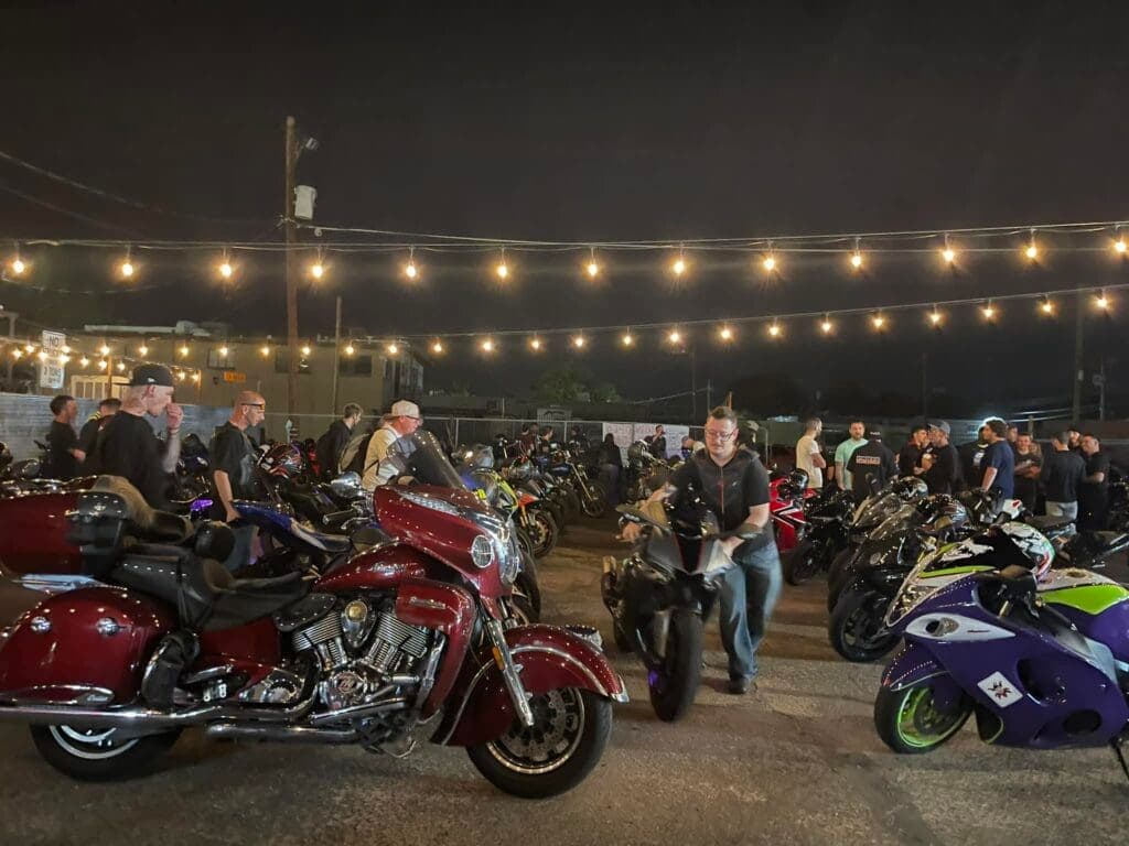 a group of people standing around a motorcycle in a parking lot