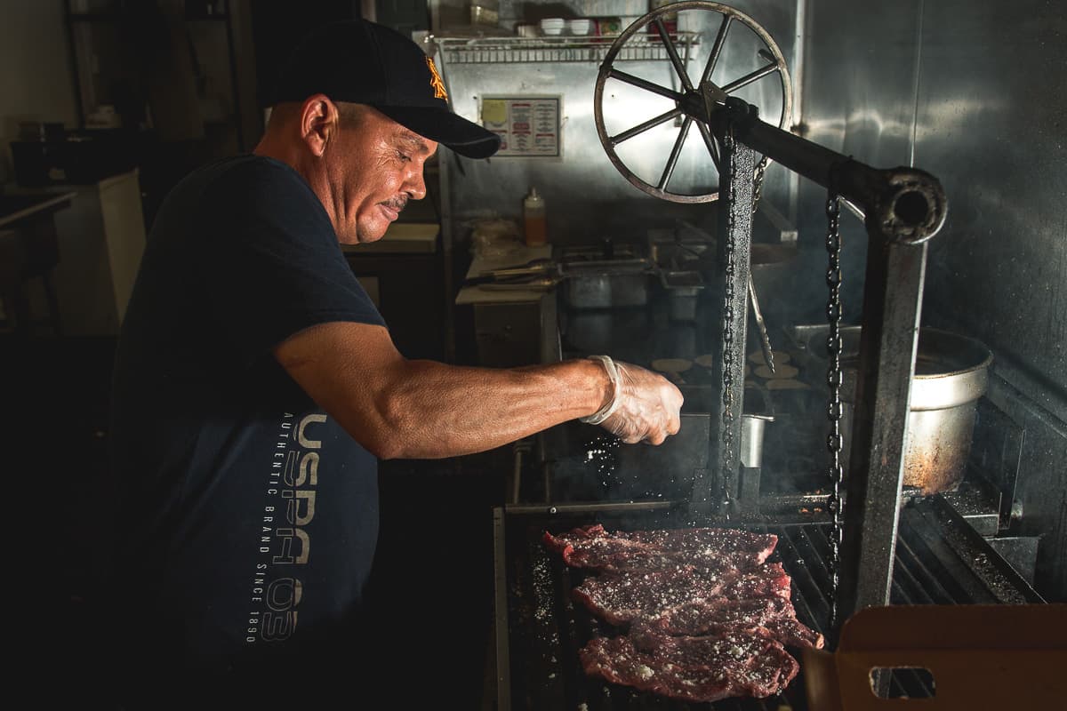 Karamelo King owner-chef Rafael Gastelum seasoning carne asada on the mesquite grill