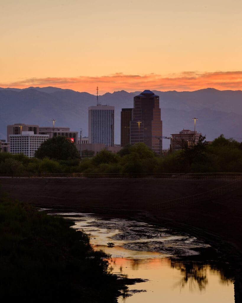 a sunset over a body of water with a city in the background