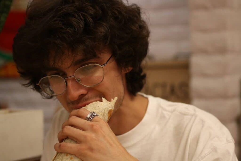 Adan Baca bites into a bean and cheese burrito at Paco’s Mexican Food (Photo by Noor Haghighi)