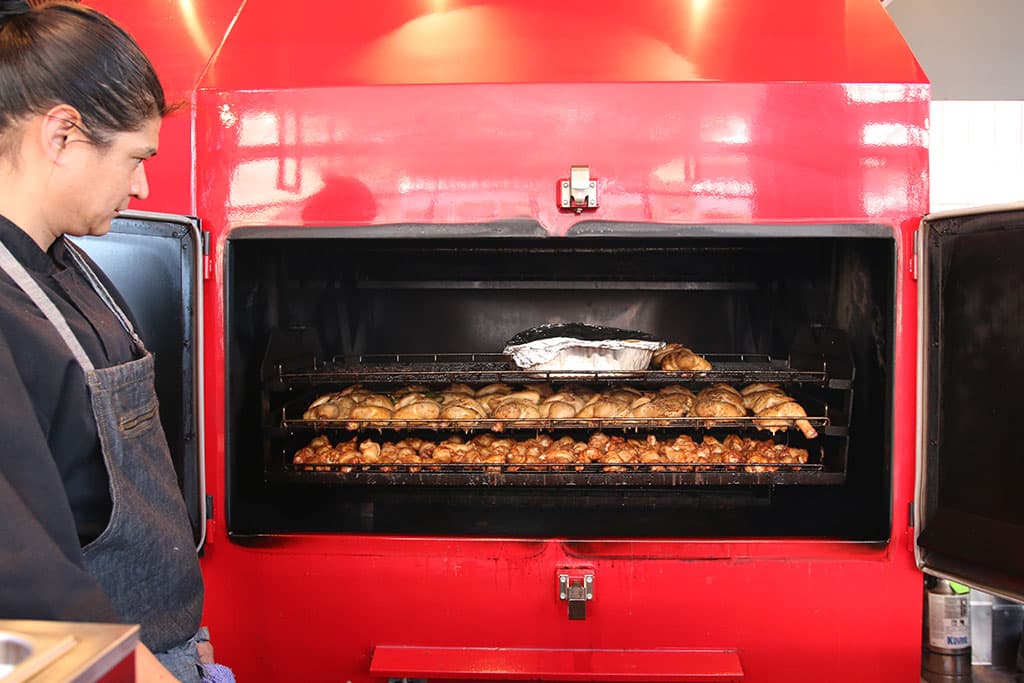 Ramiro Scavo checks o chicken smoking in the Myron Mixon Smoker (Credit: Adam Lehrman)