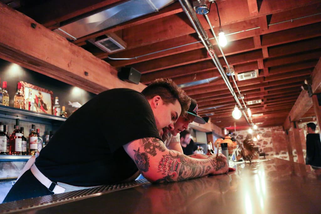 Bar Manager Nick Morris goes over the night's drink "cheats" with bartender John Holcombe.
