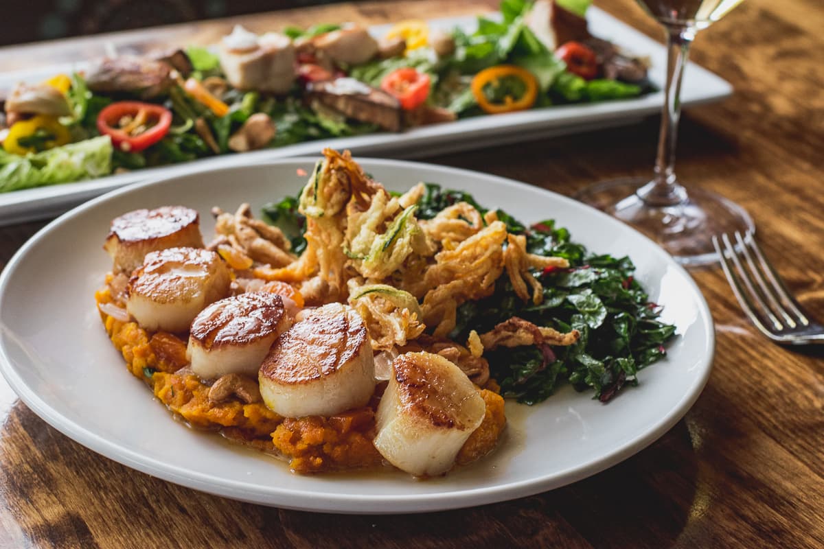 Where to eat on an expense account Seared Sea Scallops with kabocha puree, roasted cashews, shallots, Swiss chard, crispy summer and winter squashes, and dried apricot at Feast (Credit: Jackie Tran)