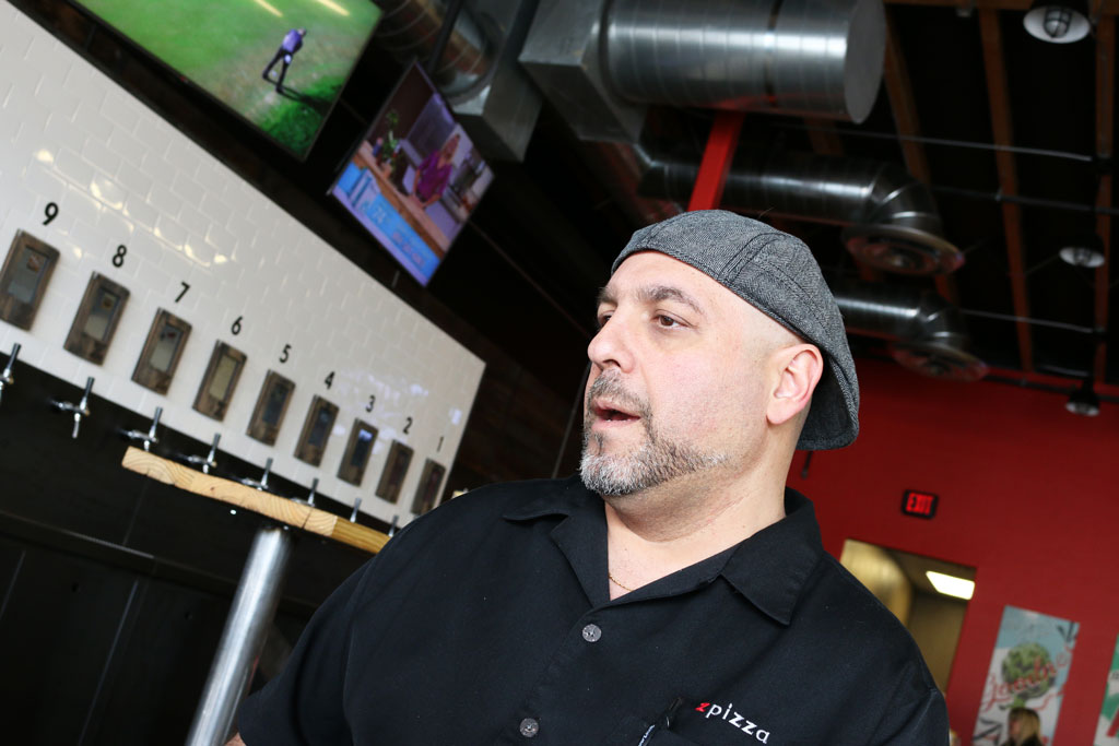 Zpizza franchise owner Rob Curcio in front of self-serve beer wall