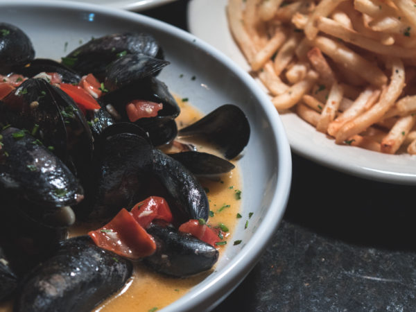 Steamed Prince Edward Island Mussels in a white wine garlic tomato beurre blanc and Roasted Garlic Fries at Wild Garlic Grill (Credit: Adam Lehrman)