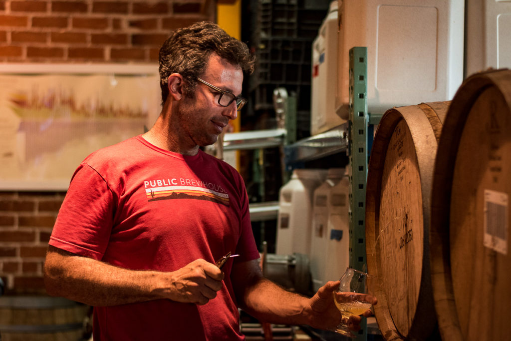 Mike Gura sampling from a barrel at Public Brewhouse (Credit: Jackie Tran)