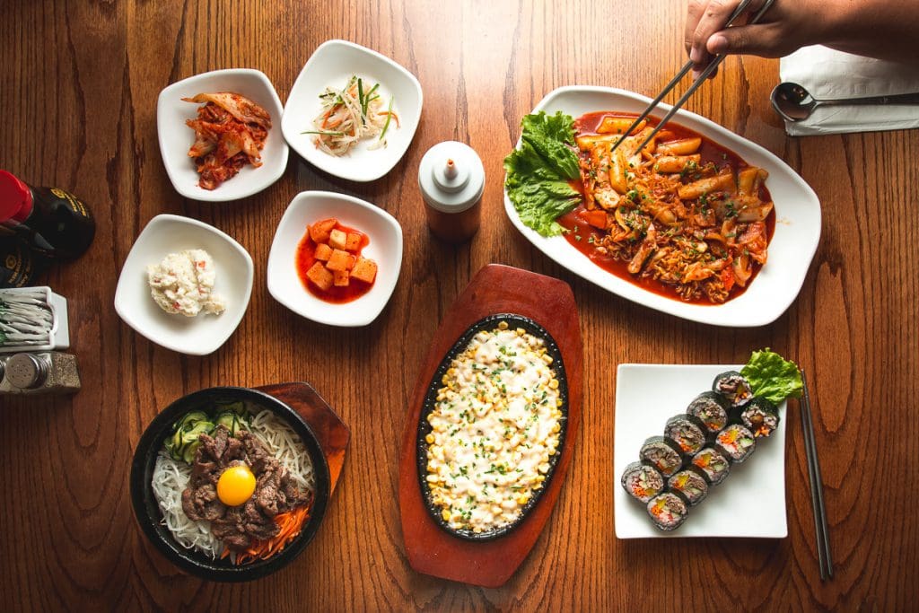 Banchan, deokbokki, dolsot bibimbap, cheese corn, and kimbop at Kimchi Time (Photo by Jackie Tran)