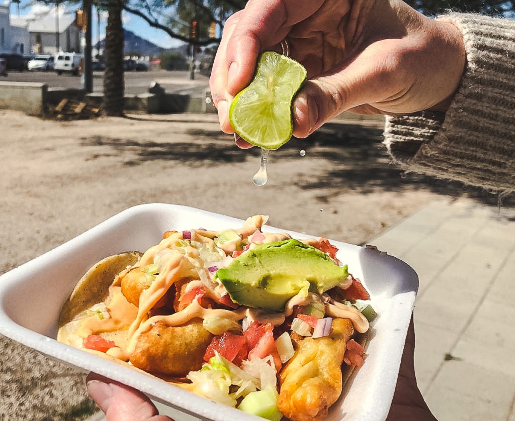 a picture of a hand squeezing a lime onto fish tacos