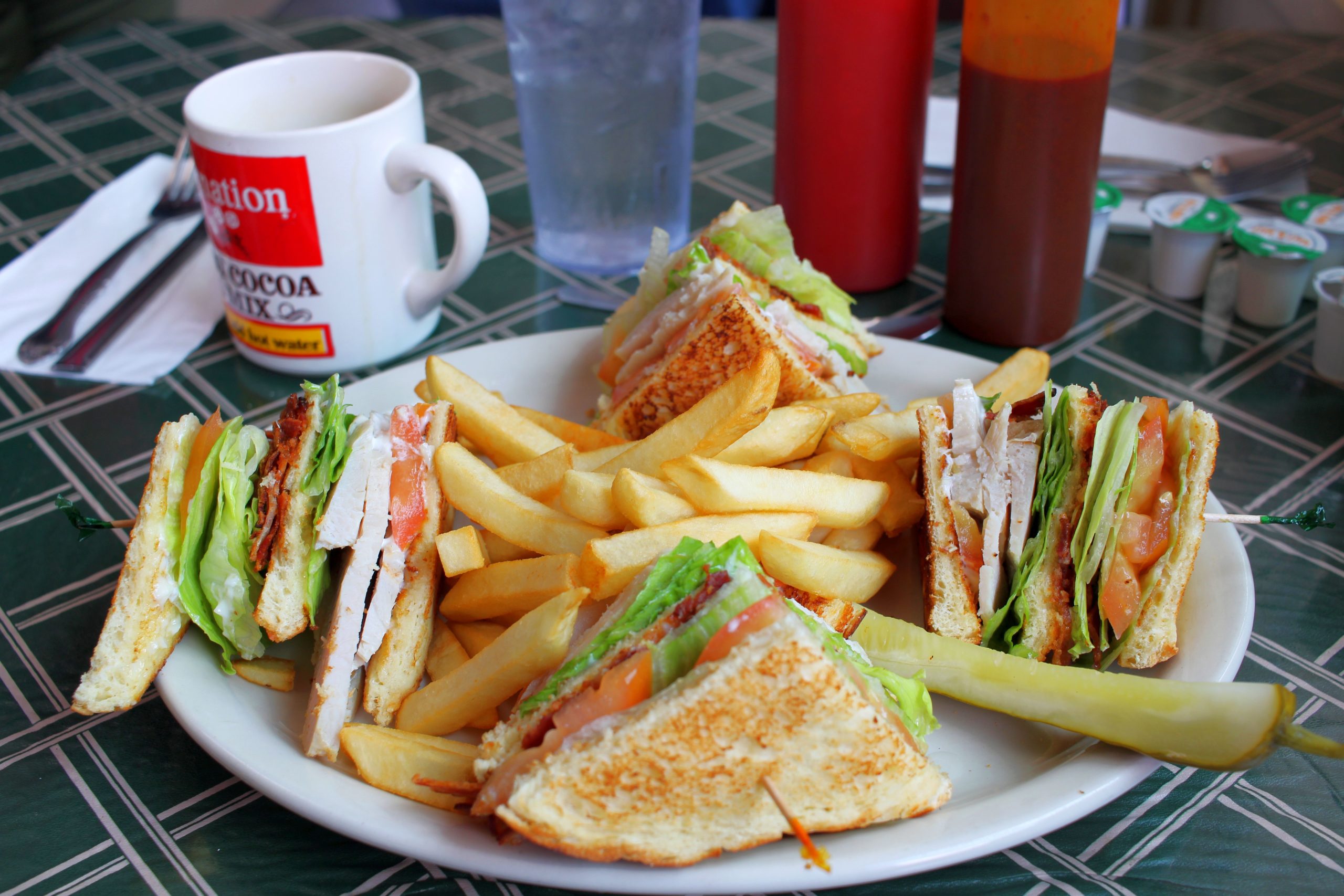 a picture of a club sandwich, fries, and a pickle