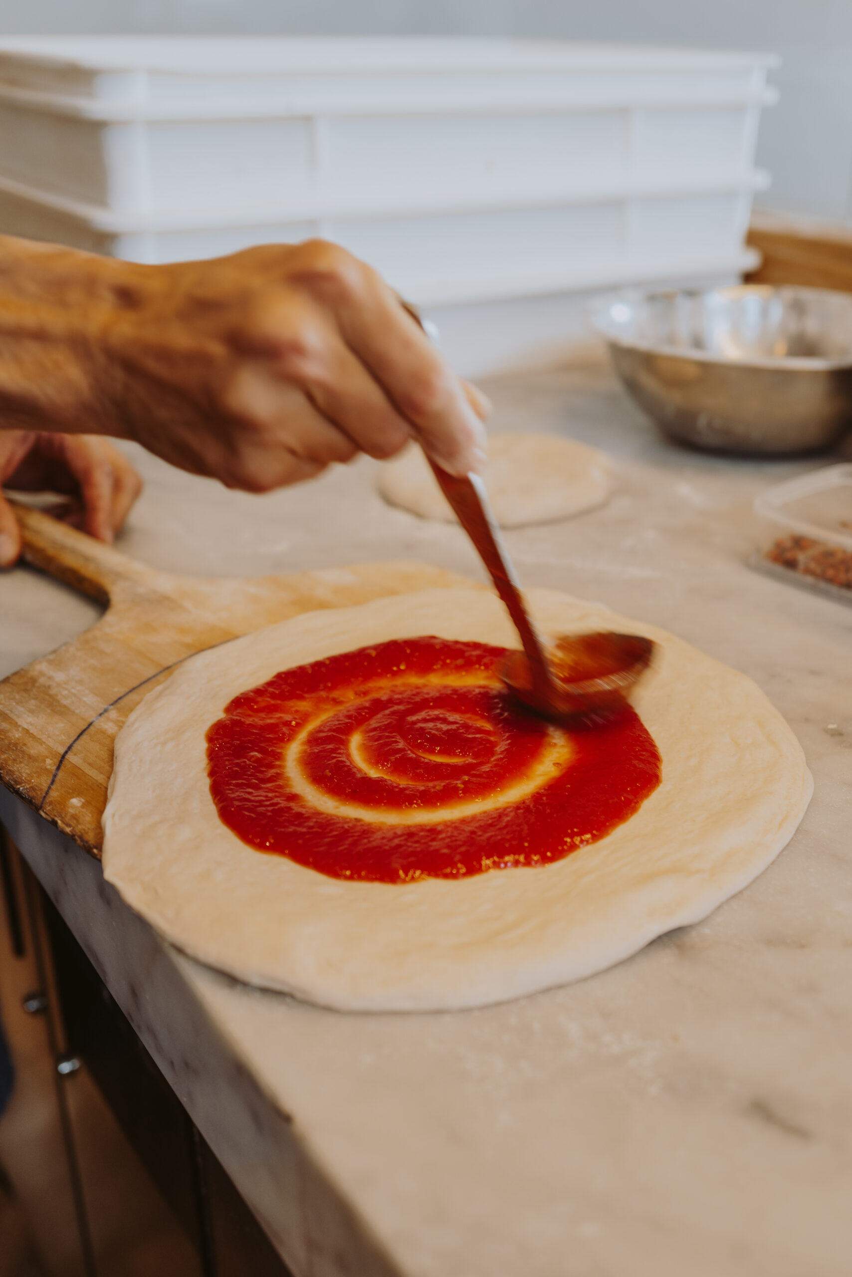 a picture of sauce being poured onto pizza dough