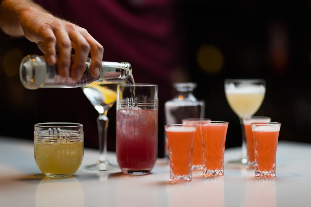 A photo of a cocktail being poured next to several other drinks