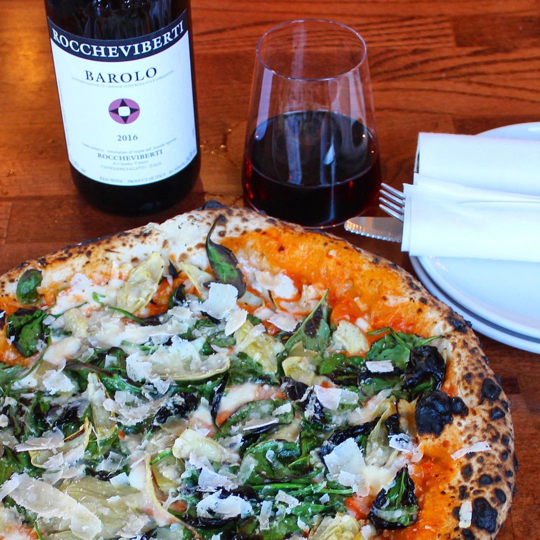 a close up of a plate of pizza and a bottle of wine