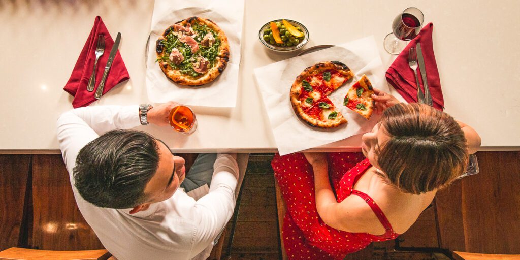A couple sharing pizza and cocktails at Reilly Craft Pizza and Drink (Photo by Jackie Tran)